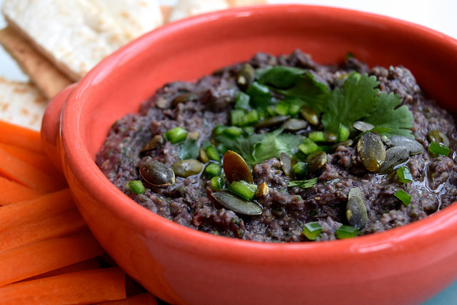Easy Black Bean Dip with Sunflower Seeds in an orange bowl.