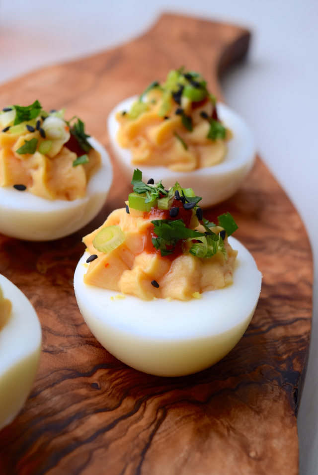 Asian devilled eggs with miso close up on a wooden serving board.