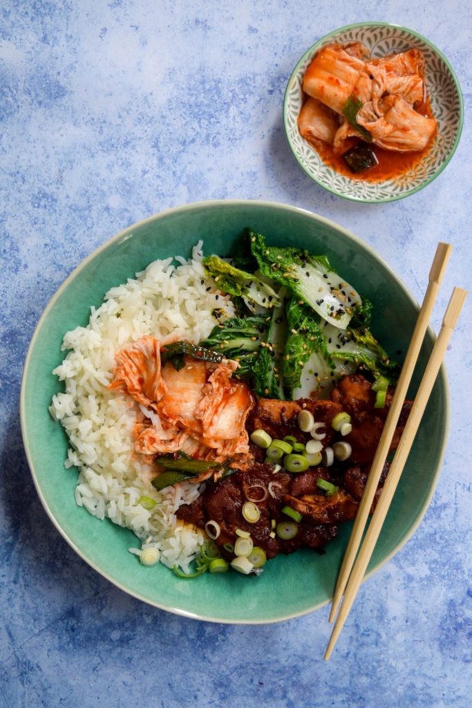 Slightly spicy slow cooker korean chicken thighs with kimchee and sesame pak choi in a rice bowl.