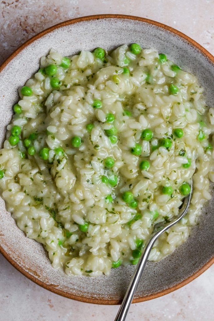 Close up of a bowl of wild garlic butter risotto with peas.