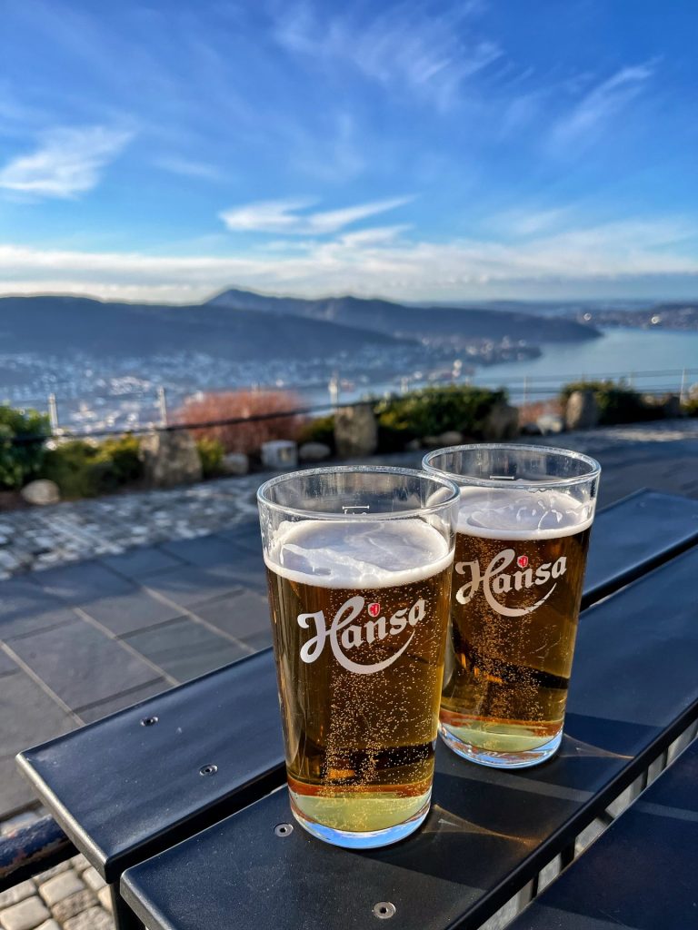 A pair of beers on a table with a view over Bergen in the background.