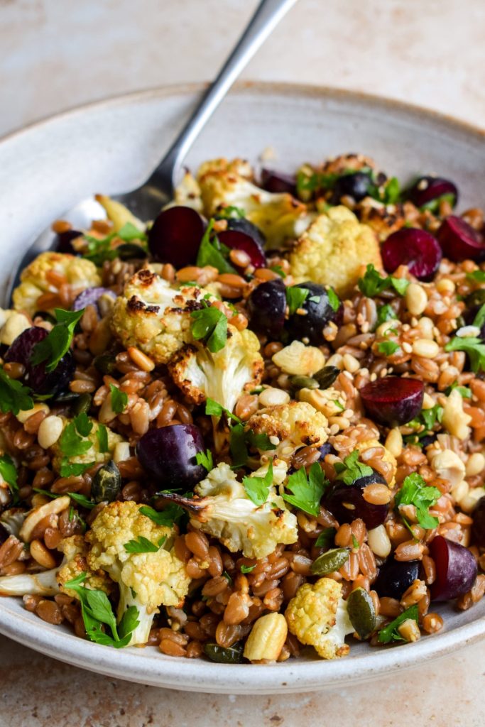 Close up of a cauliflower and grape spelt salad.