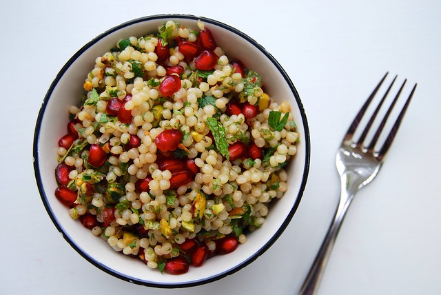 Bowl of Israeli couscous salad with pomegranate, pistachios and fresh mint.