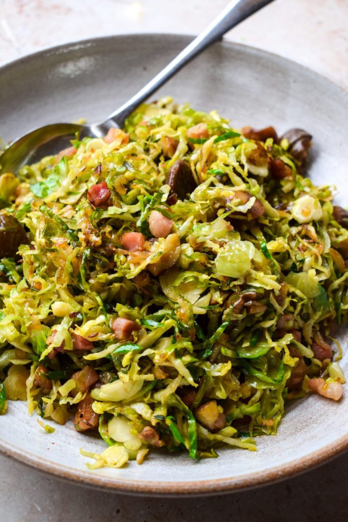 Close up of a bowl of shredded sprouts with pancetta and chestnuts.