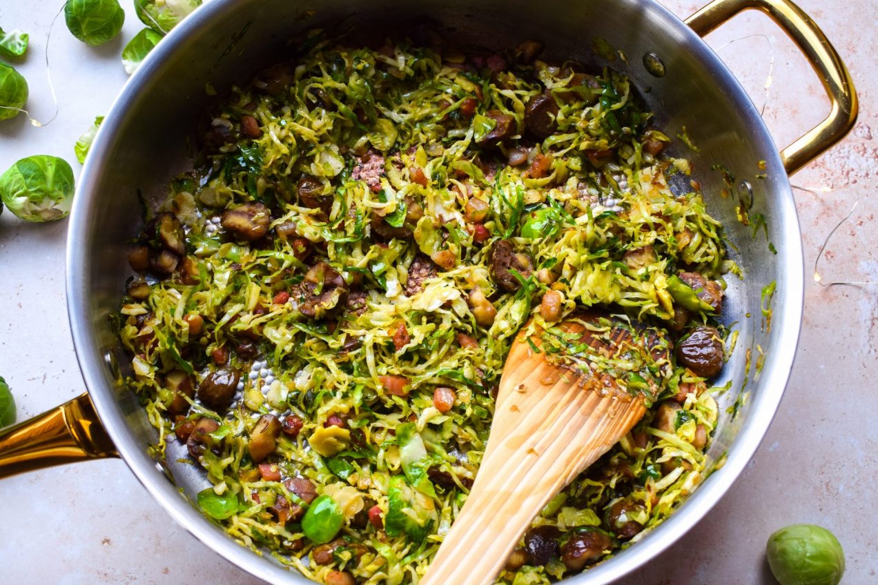 Pan of shredded sprouts being stirred with a wooden spatula.