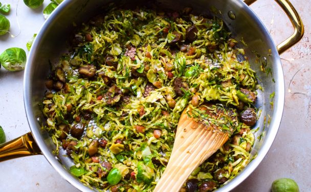 Pan of shredded sprouts being stirred with a wooden spatula.