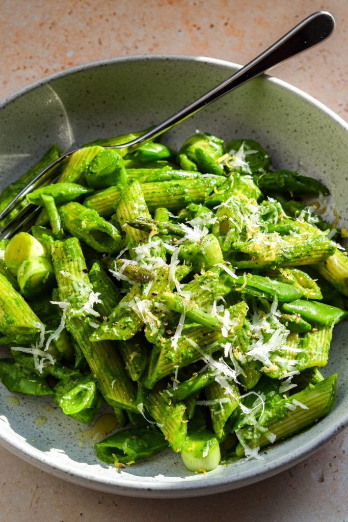 Grey stone bowl of pesto pasta tossed with spring vegetables
