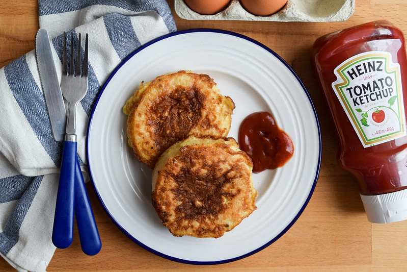 Overhead image of eggy bread crumpets with ketchup on a blue and white plate.