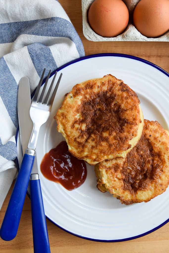 Overhead image of two eggy bread crumpets with ketchup on a blue and white plate.