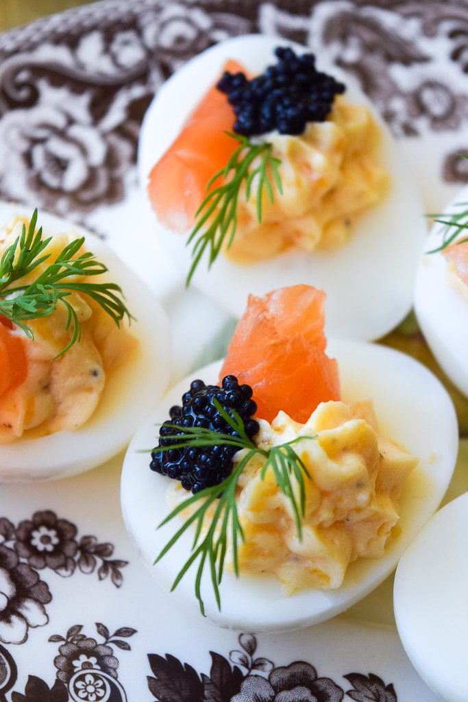 Close up of deviled eggs topped with smoked salmon, caviar and dill.