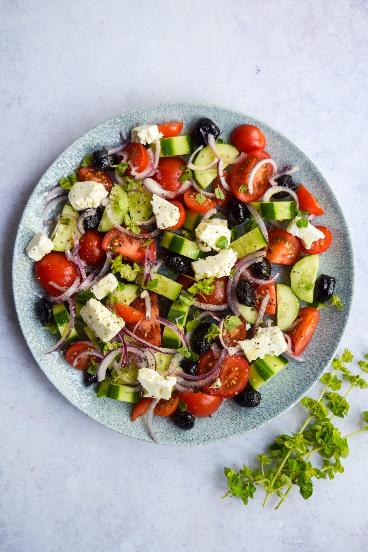 Overhead image of a greek salad on a blue plate.