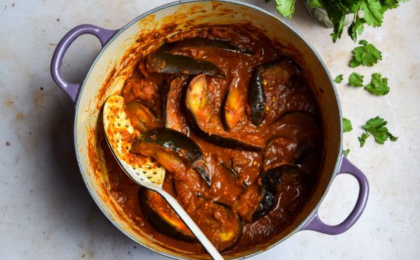 Tomato and aubergine curry pictured top down in a purple casserole dish.