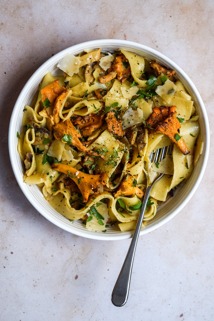 Overhead image of a bowl of pappardelle pasta with wild mushrooms, fresh thyme and parmesan shavings.
