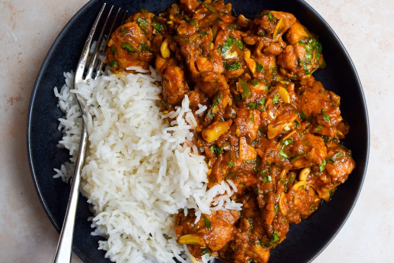 Garlic chilli chicken curry served with rice in a black bowl.
