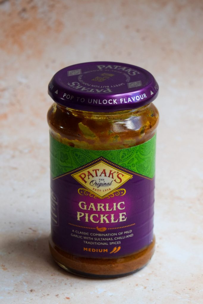 A jar of garlic pickle on a neutral background.