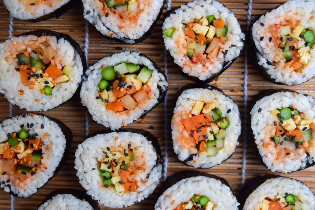 Close up of vegetarian kimbap rolls on a sushi rolling mat.