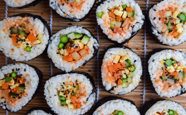 Close up of vegetarian kimbap rolls on a sushi rolling mat.