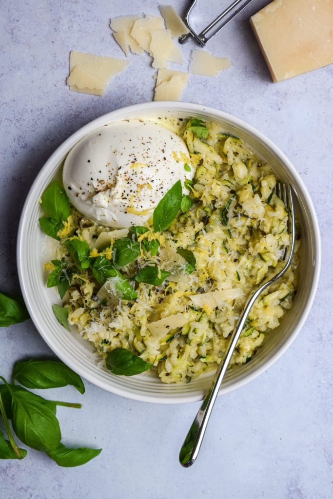 Bowl of courgette risotto with lemon zest, basil and a burrata.