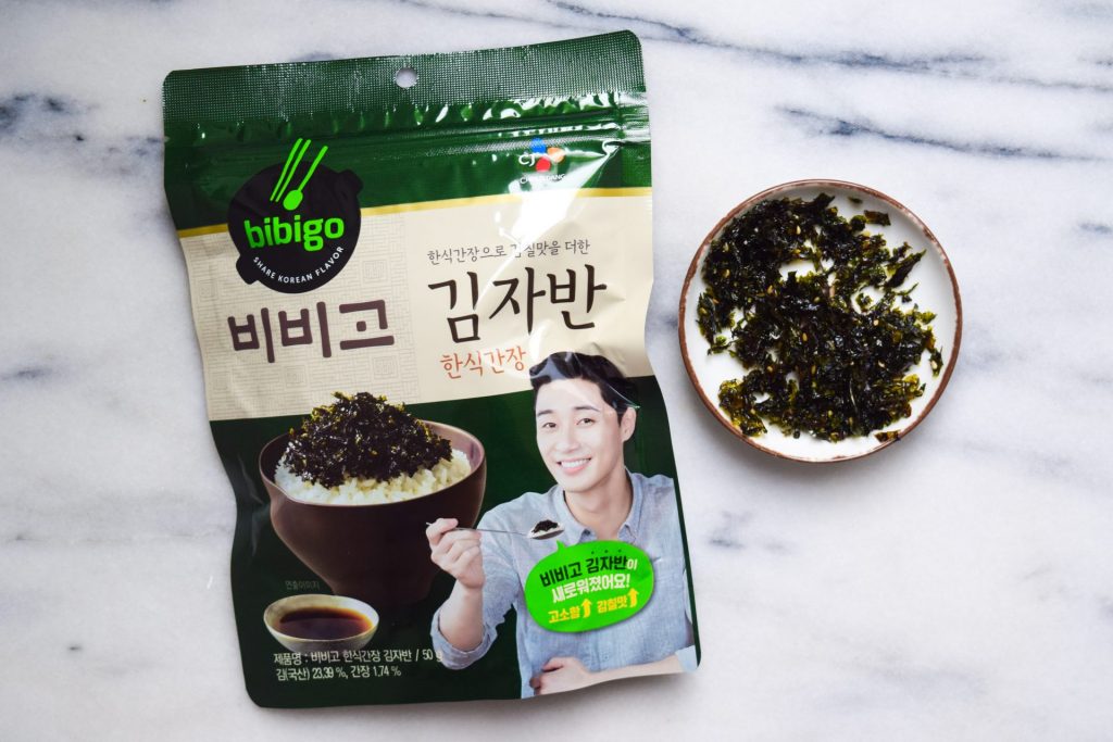 Bag of Korean dried seaweed with sesame seeds next to a small dish of it out of it's packet.