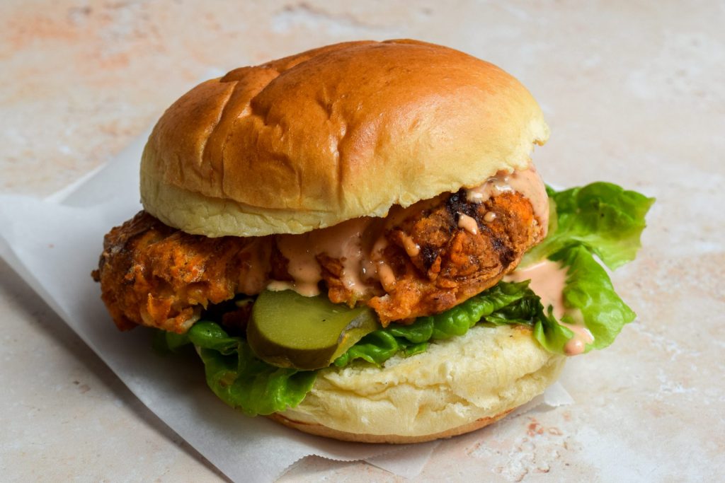Close up of an air fryer chicken sandwich with lettuce and kosher pickles.