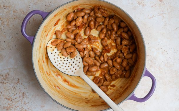 Braised borlotti beans in a purple casserole dish.