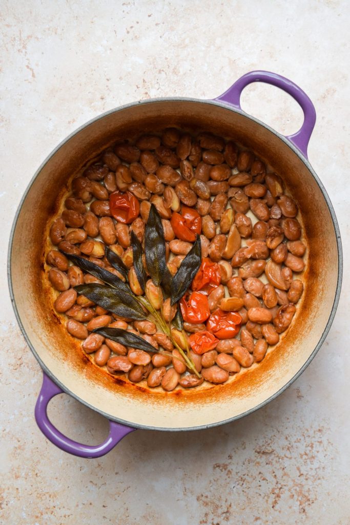 Borlotti beans braised in a casserole dish with sage and cherry tomatoes.