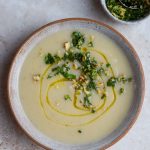 Bowl of celeriac soup topped with walnut gremolata with a small bowl of gremolata to one side.