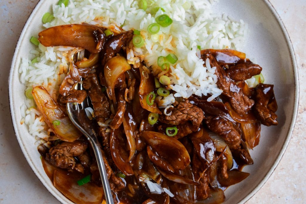 Close up of Chinese beef and onion with jasmine rice.