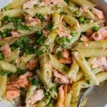 Creamy salmon, pea and lemon penne in a white bowl.