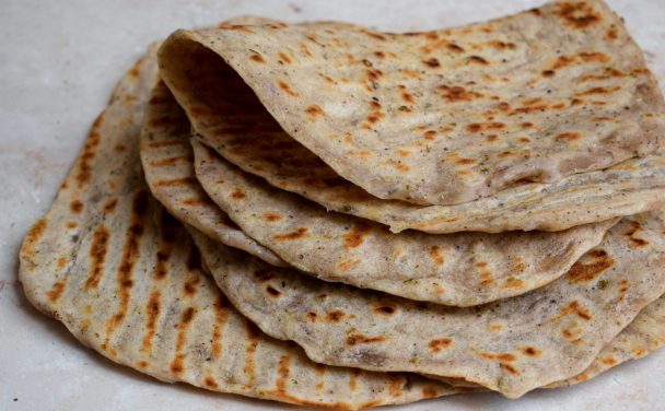Pile of folded flatbreads on a neutral background.