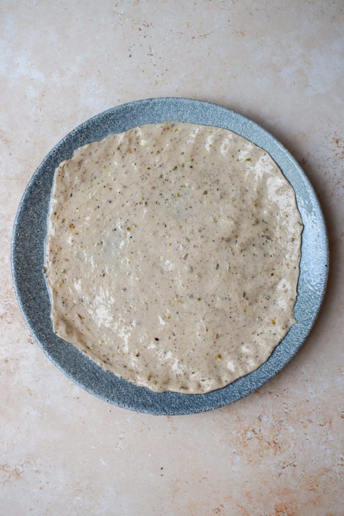 Flatbread dough stretched out on a blue plate.