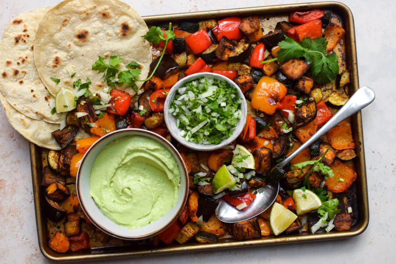Sheet pan vegetable tacos served with avocado crema and charred tortillas.