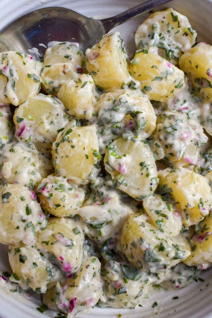 Close up of a potato salad with mayonnaise and herbs.