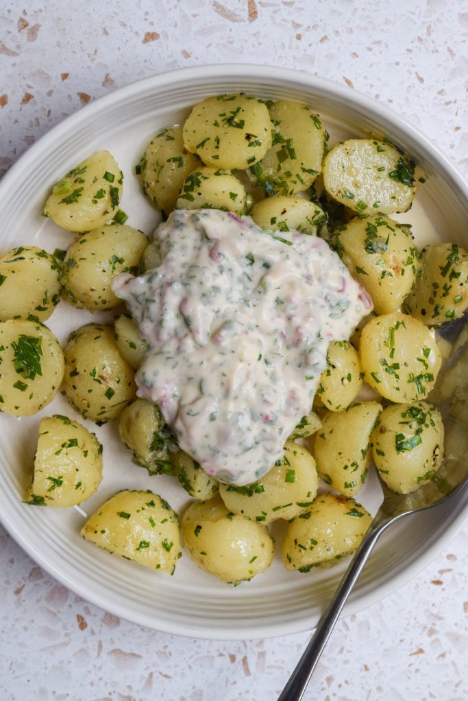 Dressed potatoes with a dollop of mayonnaise ready to be mixed into a potato salad.