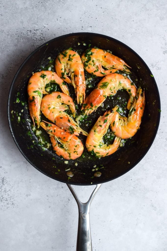 Garlic butter prawns with parsley in a frying pan.
