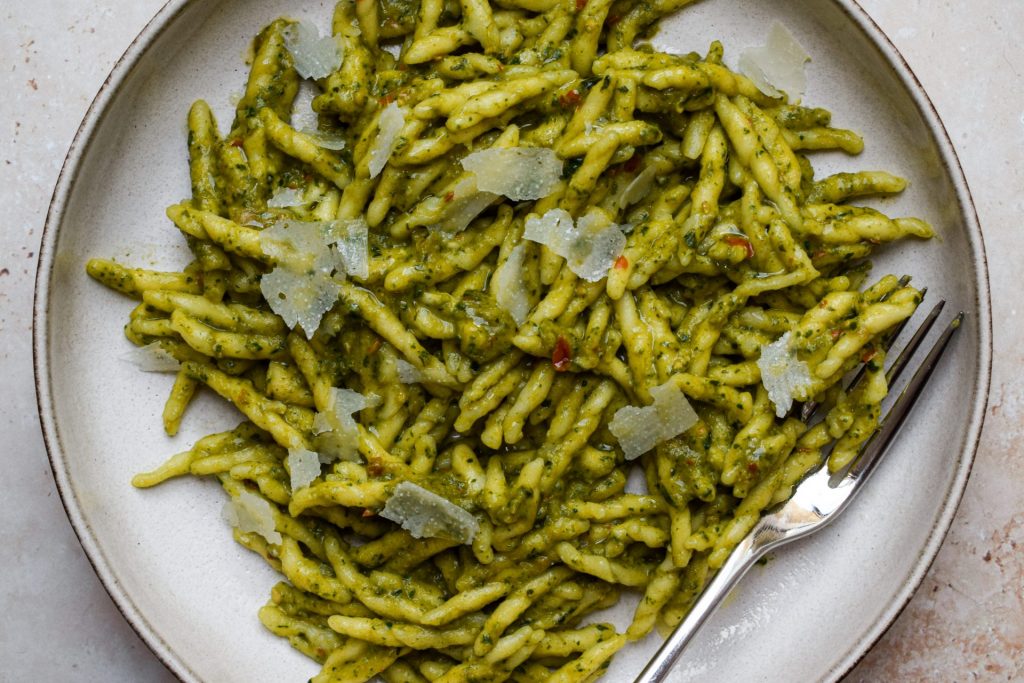 Close up of a bowl of pasta shapes tossed with pesto.