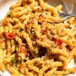 Plate of pasta with Sicilian tomato and almond pesto with toasted breadcrumbs pictured in direct sunlight.