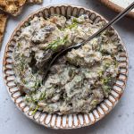 White bowl of mackerel pate topped with fresh dill on a grey background.
