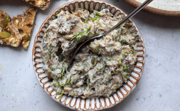 White bowl of mackerel pate topped with fresh dill on a grey background.
