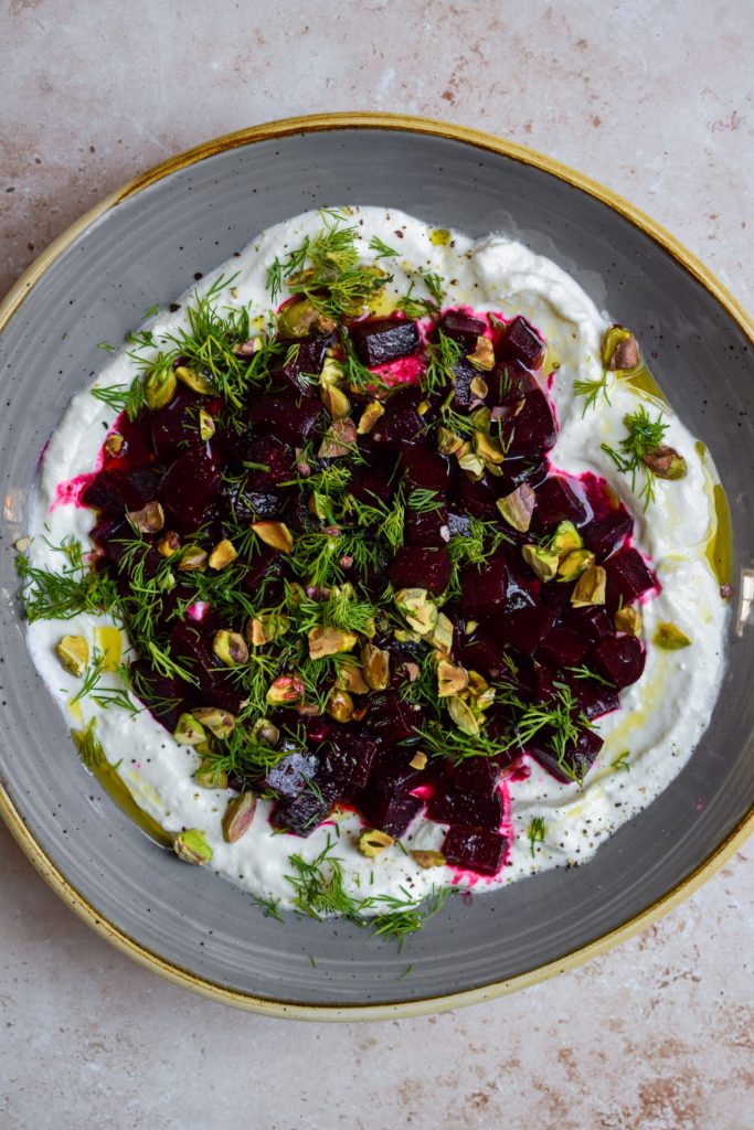Grey bowl of beetroot and herbs piled onto whipped feta.
