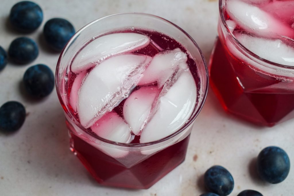 Glass of damson cordial with ice cubes.