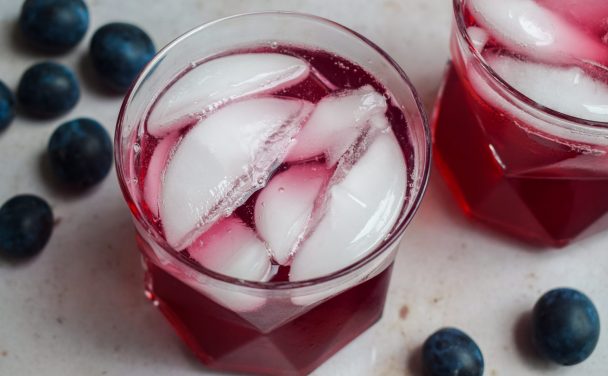 Glass of damson cordial with ice cubes.