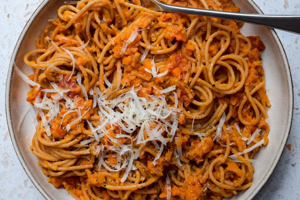 Red lentil ragu pasta topped with grated cheese.