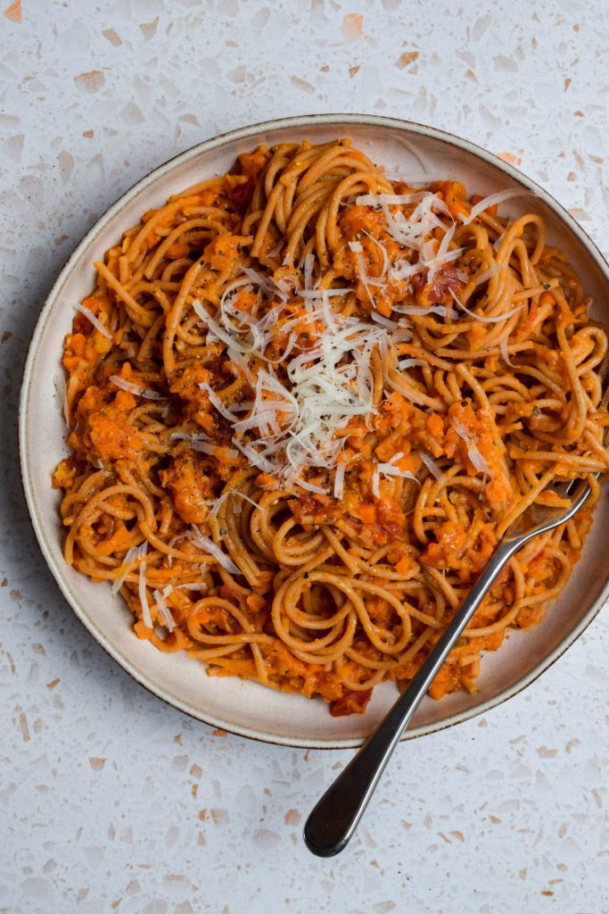 Bowl of red lentil ragu mixed with wholemeal spaghetti.