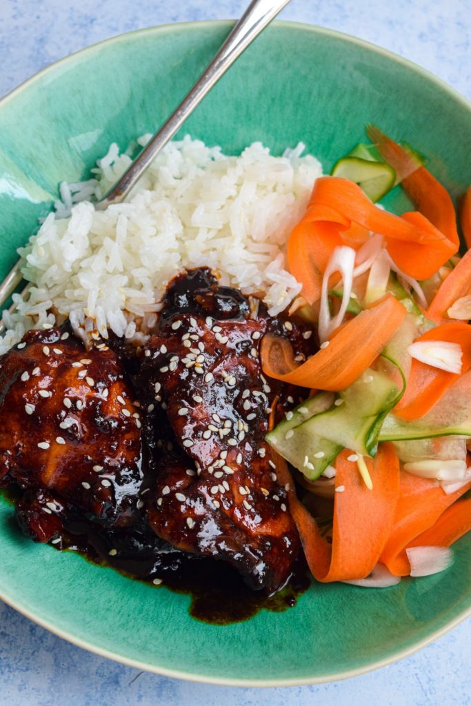 Pressure cooked chicken in a Korean sauce with rice and vegetables in a blue green bowl.
