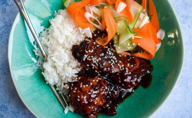 Blue bowl of Korean chicken, rice and pickled vegetables.
