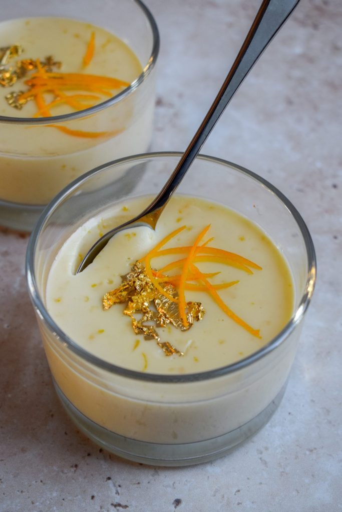 Close up of a clementine posset with a silver spoon digging into it.