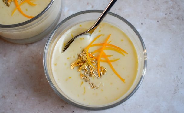Close up of a Clementine Posset topped with orange shreds and gold leaf.