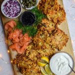 Wooden serving board of latkes, smoked salmon and caviar.