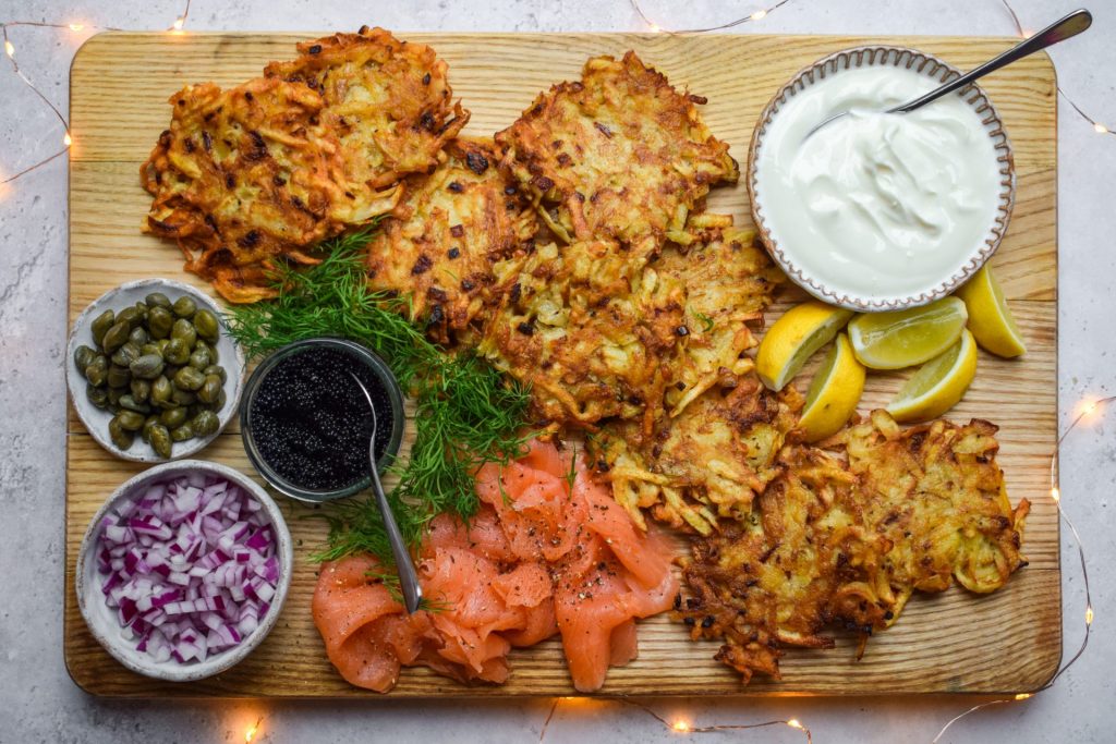 Wooden board of potato latkes with all the trimmings.